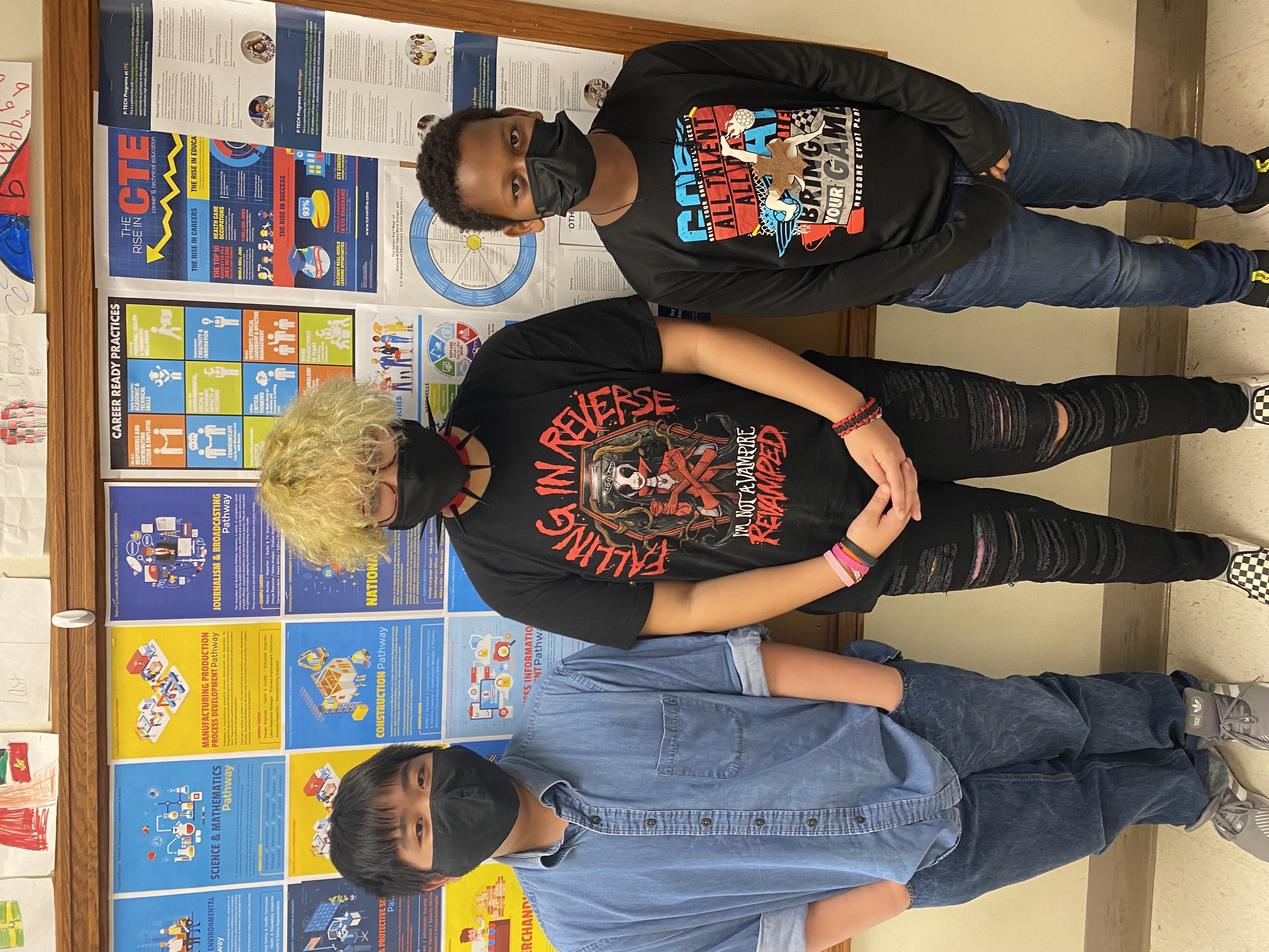 This is a photo of three students standing in front of a bulletin board covered in posters featuring career ready practices.