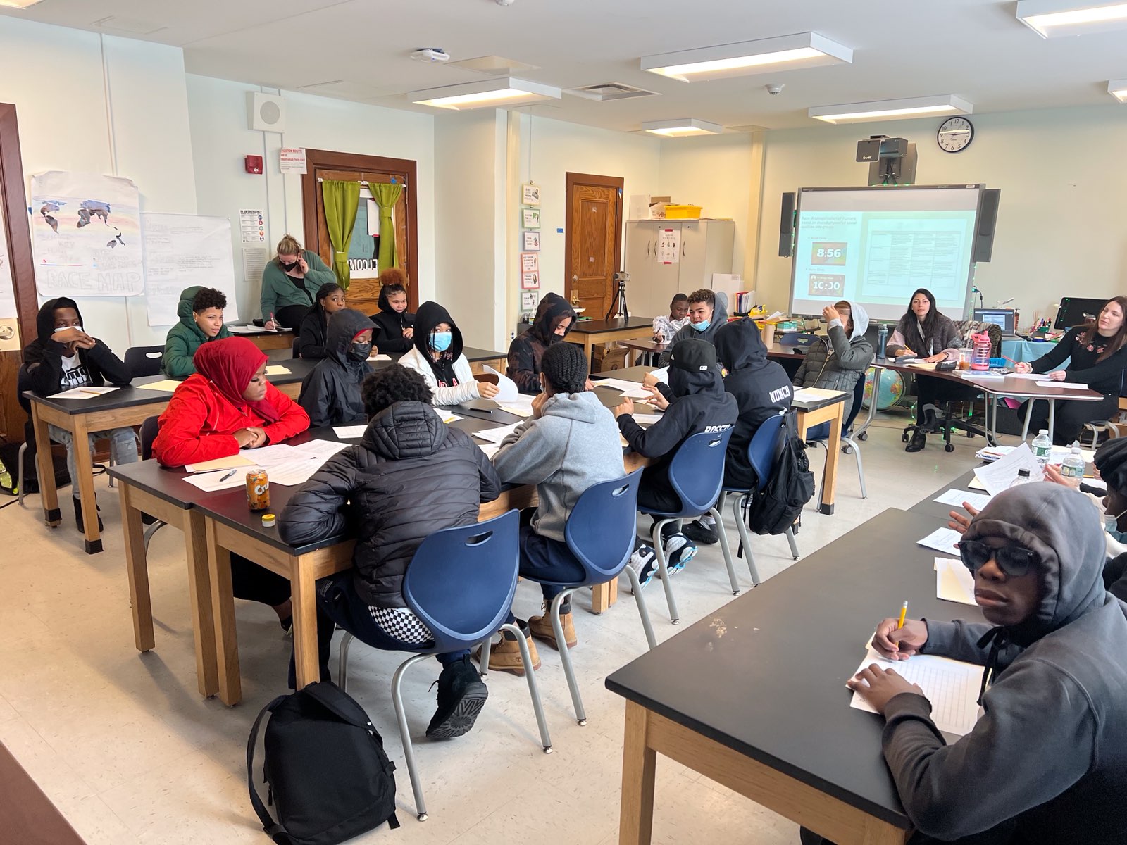 This is a photo of a classroom of students, sitting in rows of desks, looking at each other as they have a class discussion.