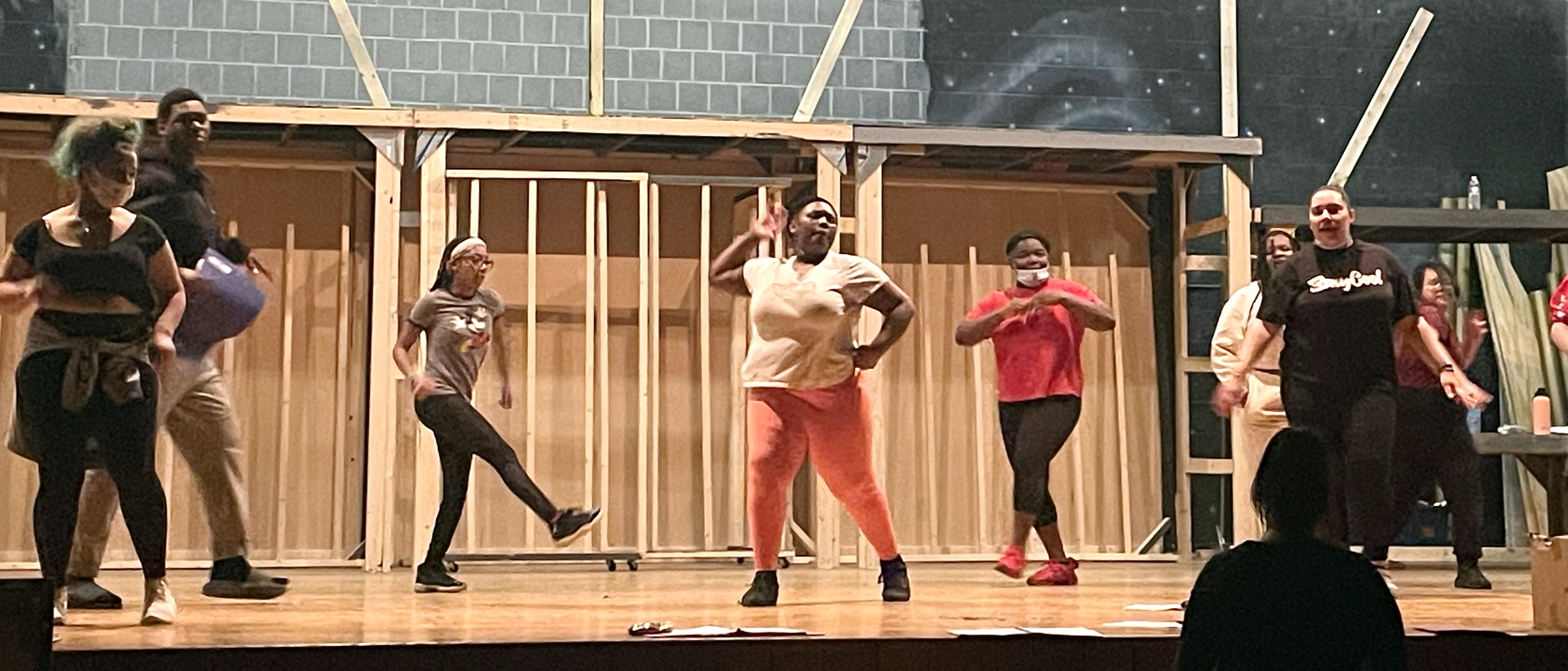 This is a photo of a group of PSLA students practicing a dance number on their school stage in preparation for their spring musical.
