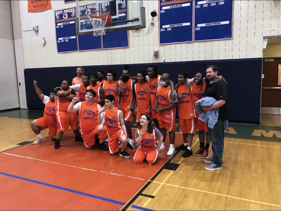 This is a team photo of the Nottingham Unified Basketball Team, standing in two rows on the school's basketball court.