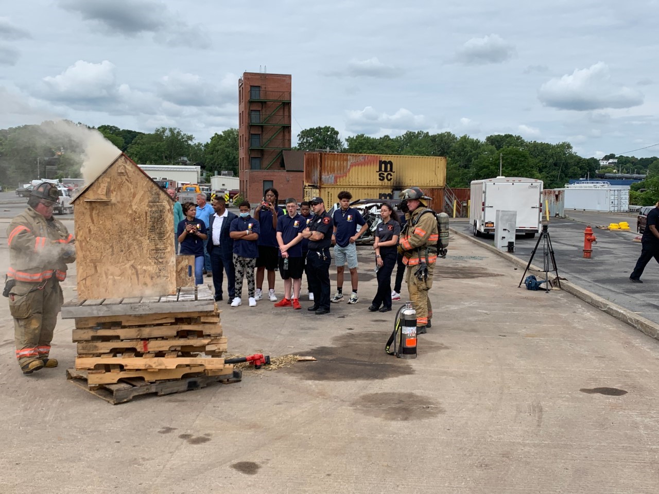 This is a photo of a group of Fire Rescue students watching Syracuse Firefighters demonstrate how they extinguish a fire.