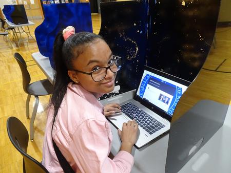 This is a photo of a female student at Clary sitting at a computer in a voting station set up in her school's gym.