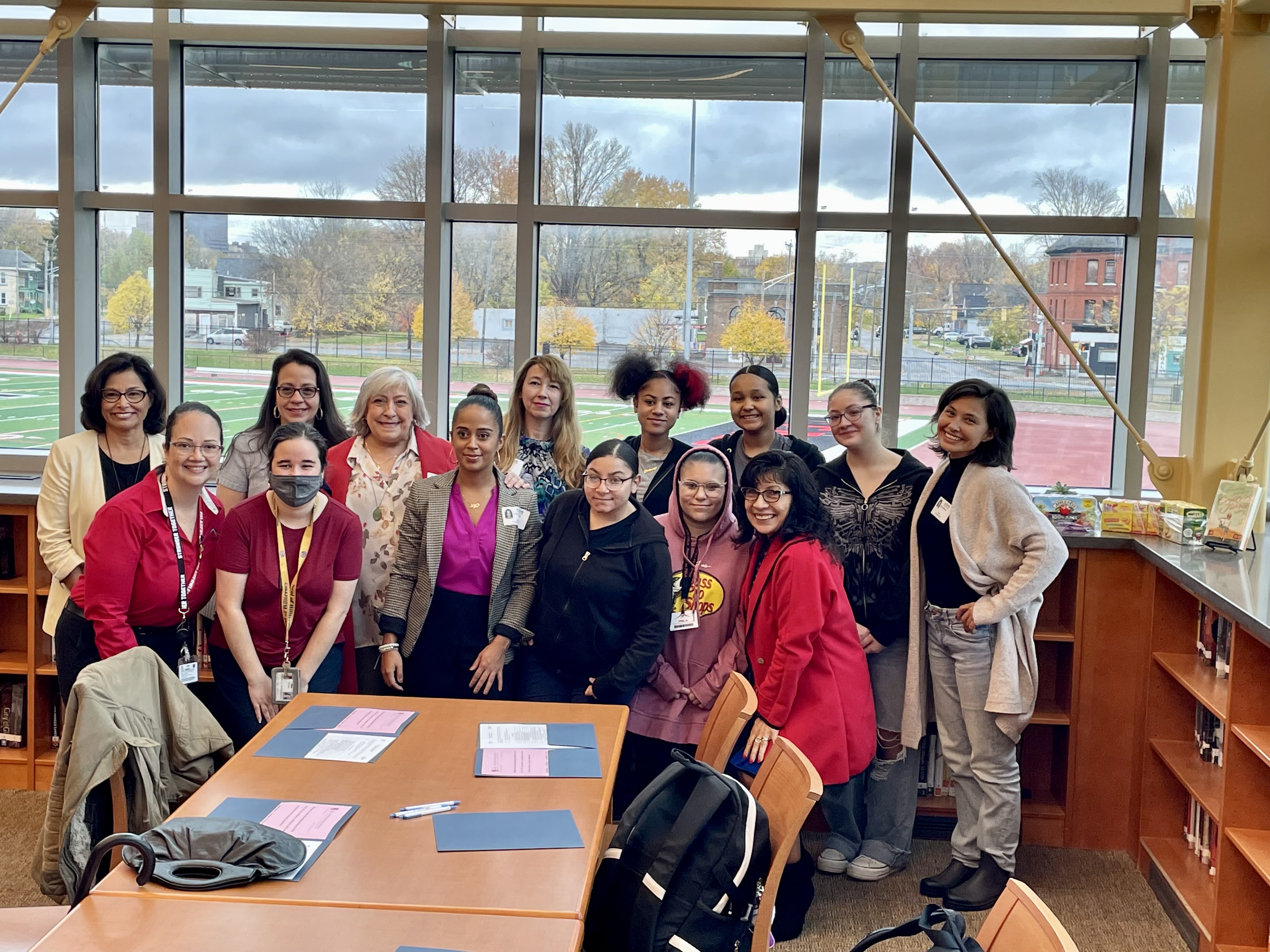 This is a photo of PSLA at Fowler students and mentors standing in the school's library in a posed photo.