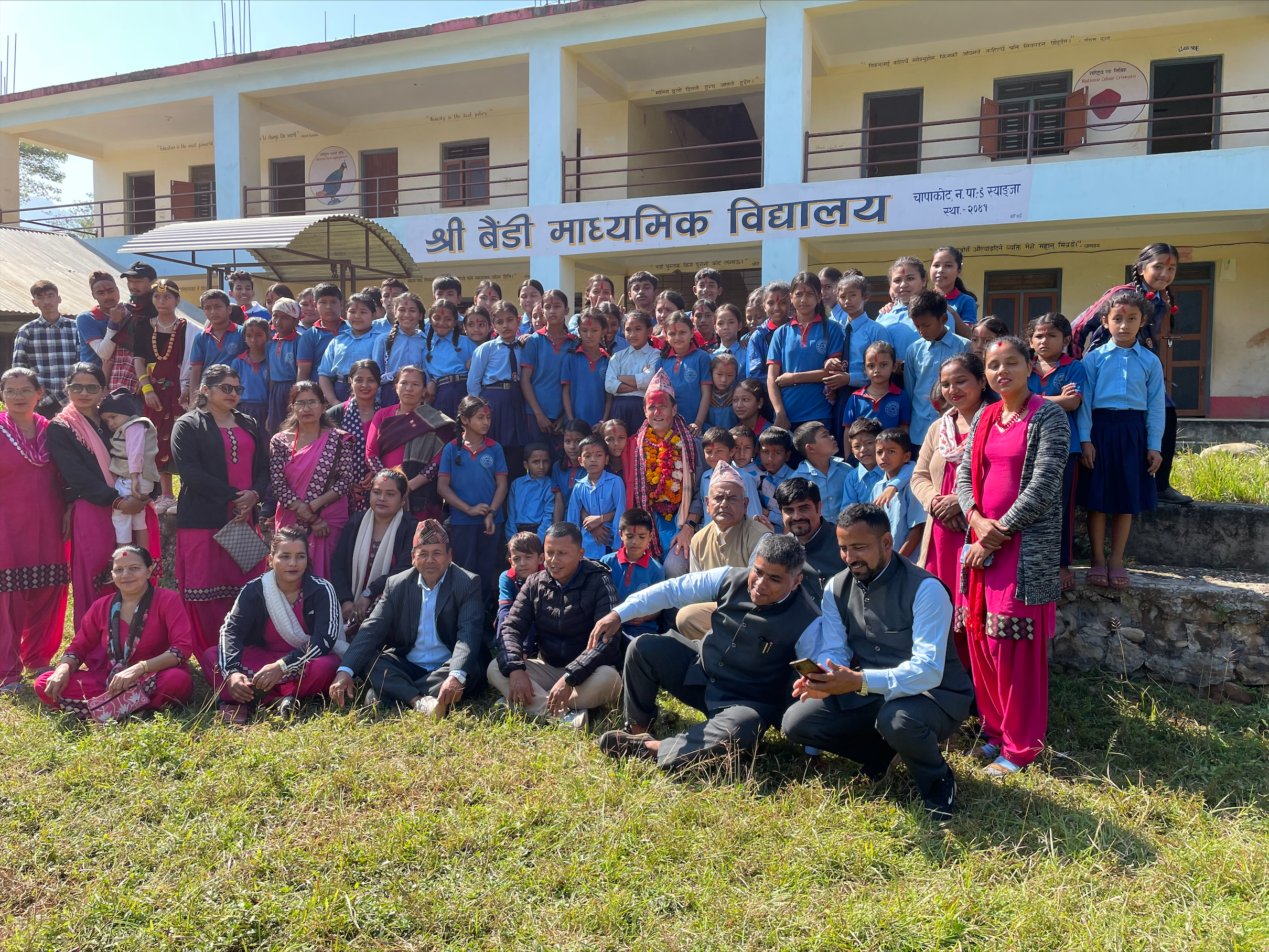 This is a photo of a group of students and staff standing outside a school in Nepal.