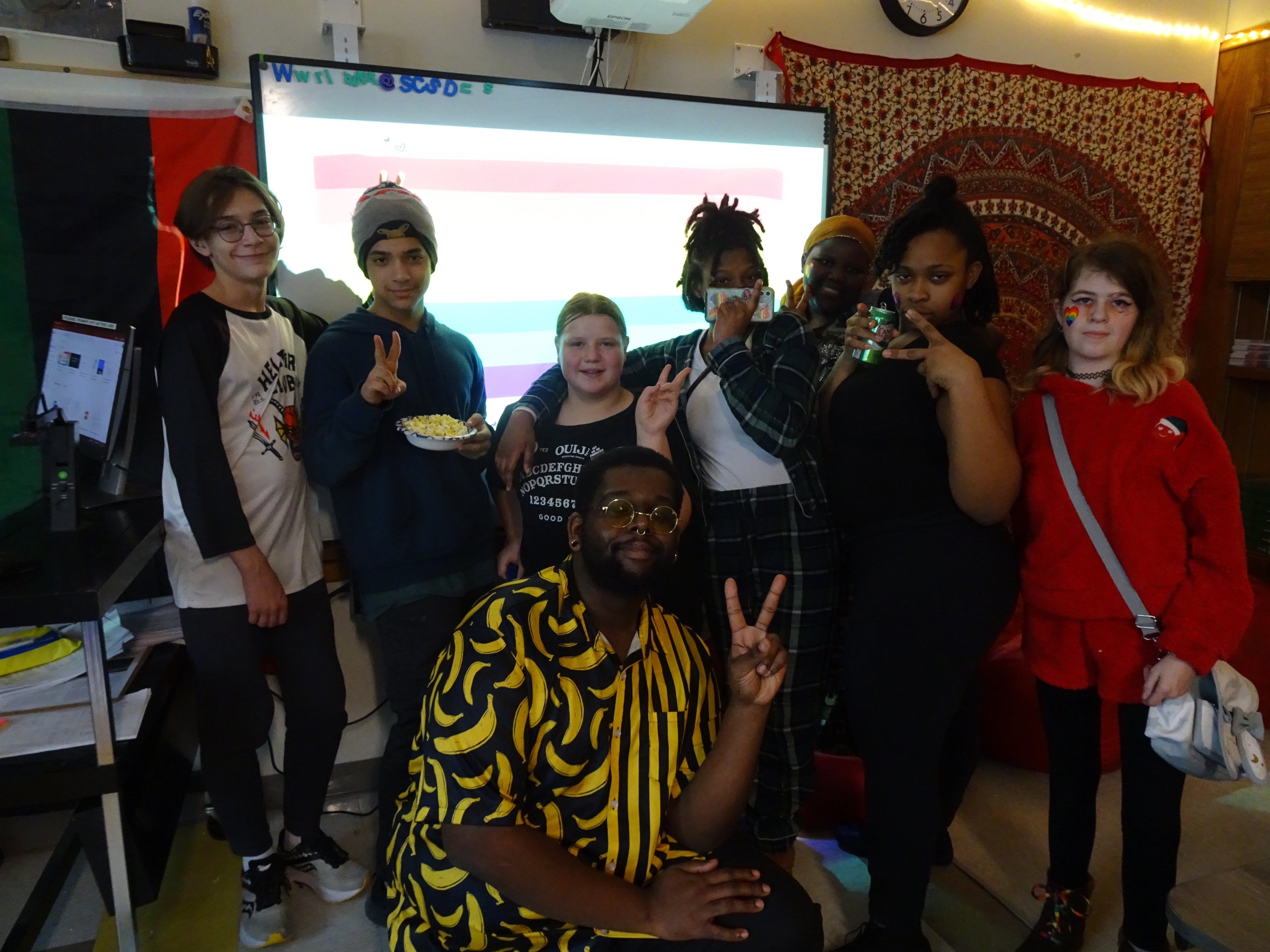 This is a photo of a group of Ed Smith students gathered together, holding their hands in peace signs and smiling at the camera.