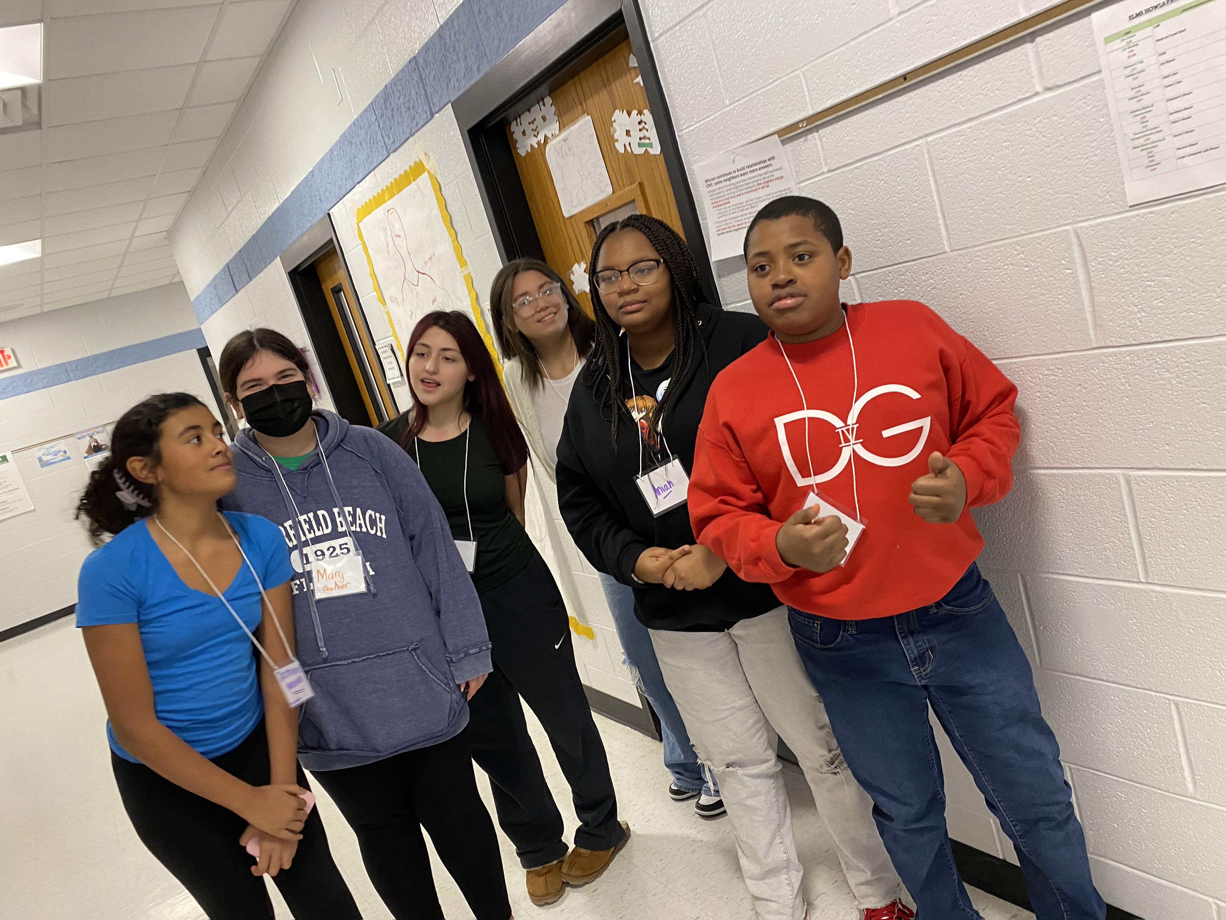 This is a photo of a group of students standing in a school hallway, smiling at the camera.