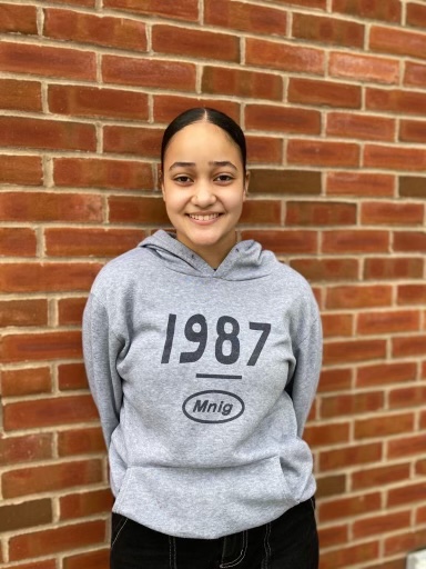 This is a photo of ITC student Destinyi Fernandez standing in front of a brick wall smiling.