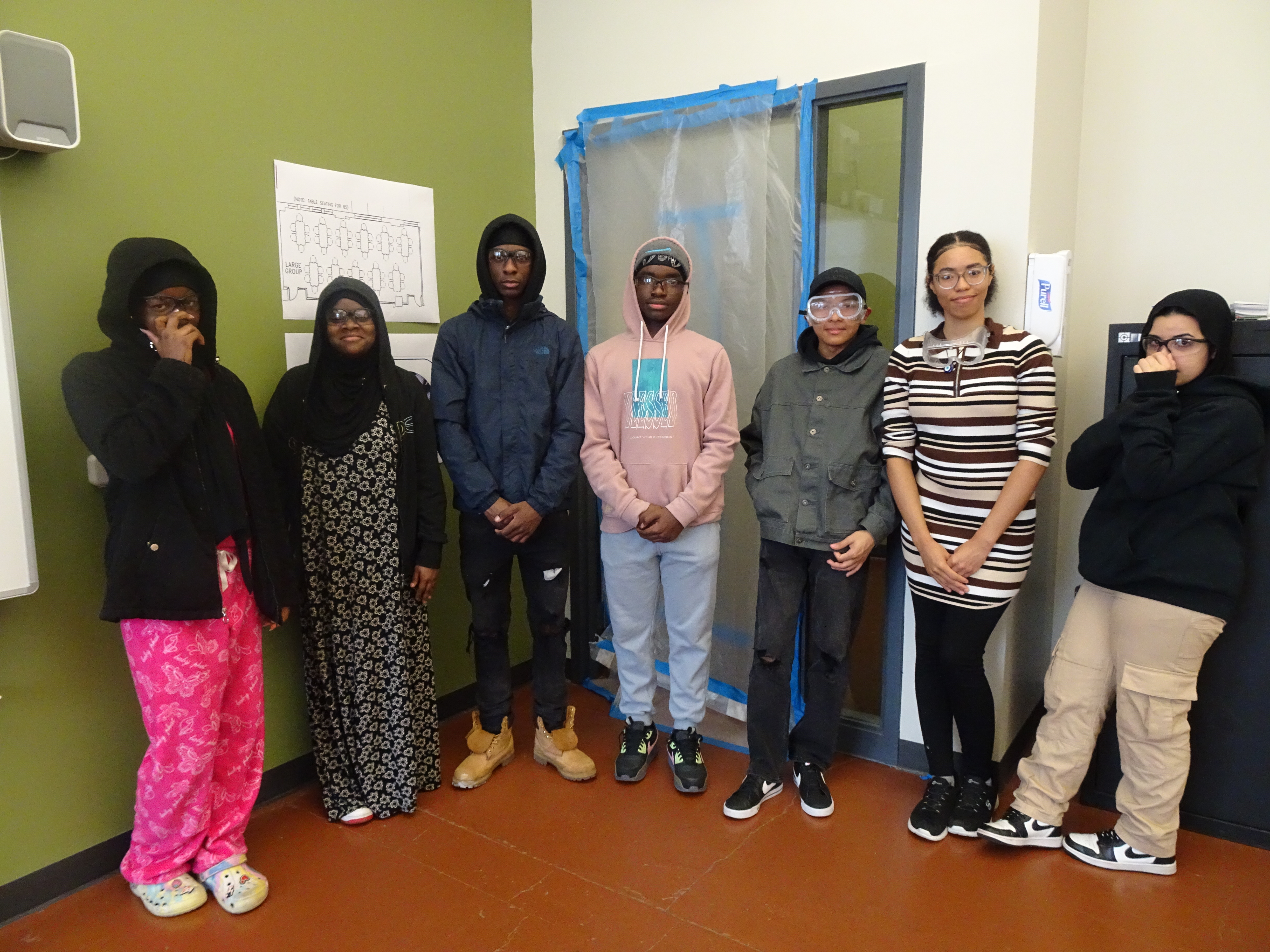 This is a photo of 7 Nottingham students lined up in front of a door that they had just taped up as part of a Lead Training course.