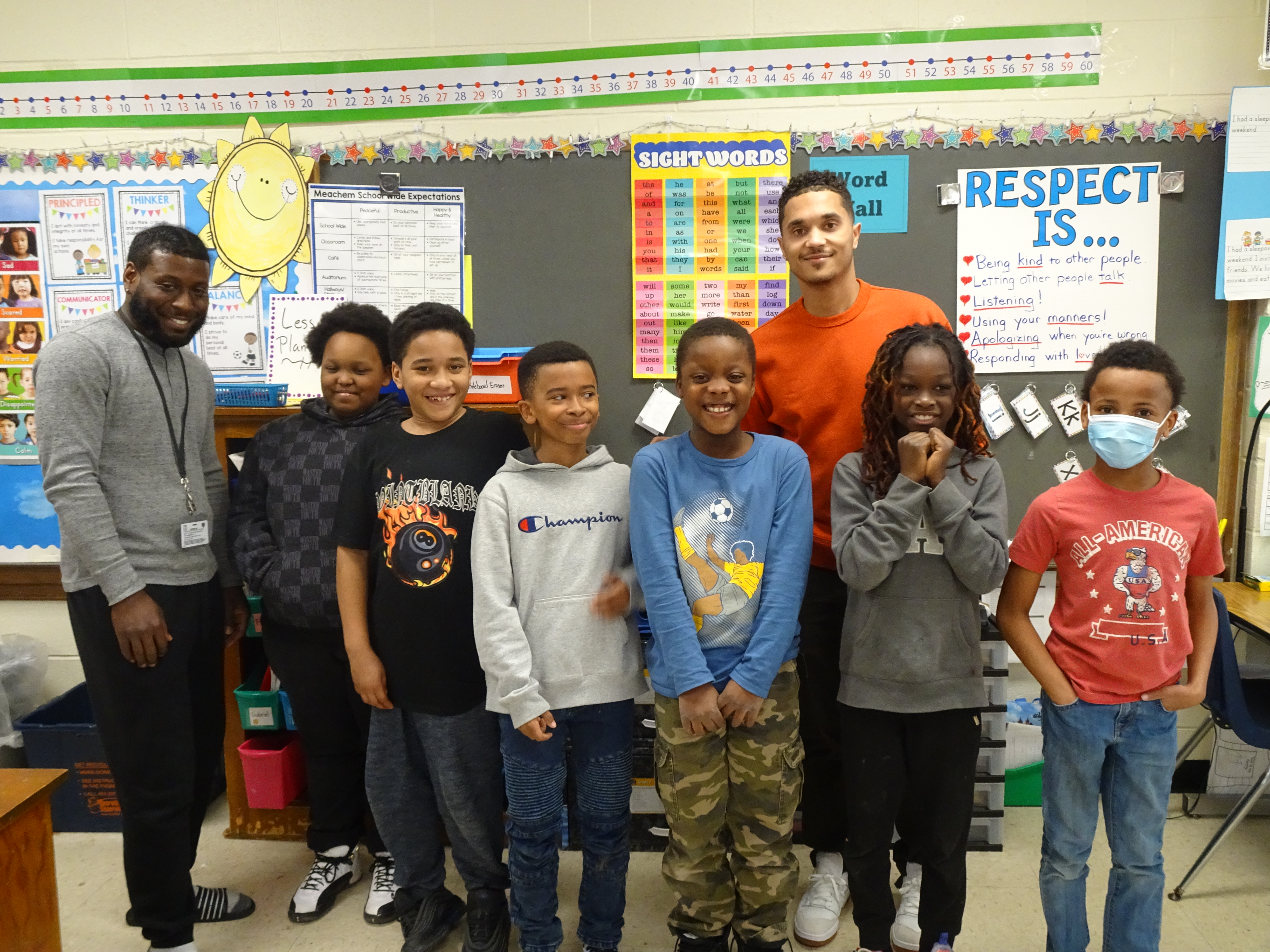 This is a photo of a group of Building Men students at Meachem Elementary, posing in a classroom with their two staff advisors.