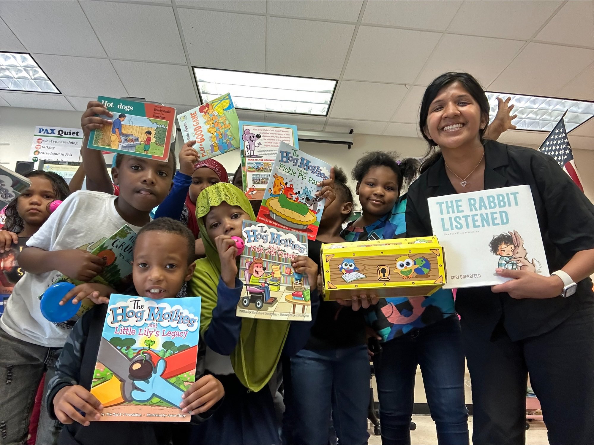 This is a photo of a group of students holding up books and smiling at the camera.