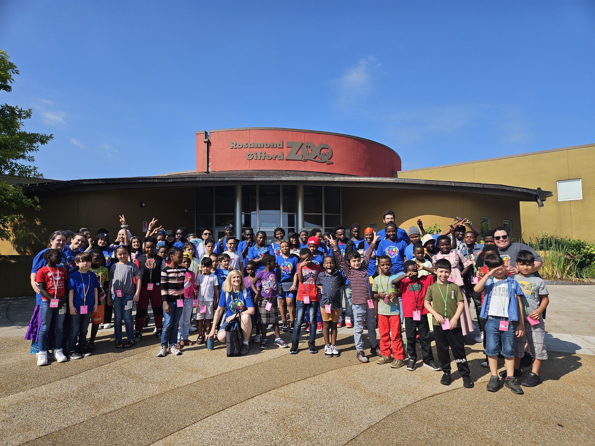 This is a photo of students from the Institute for Language & Culture standing in front of the entrance to the Rosamond Gifford Zoo and smiling at the camera.