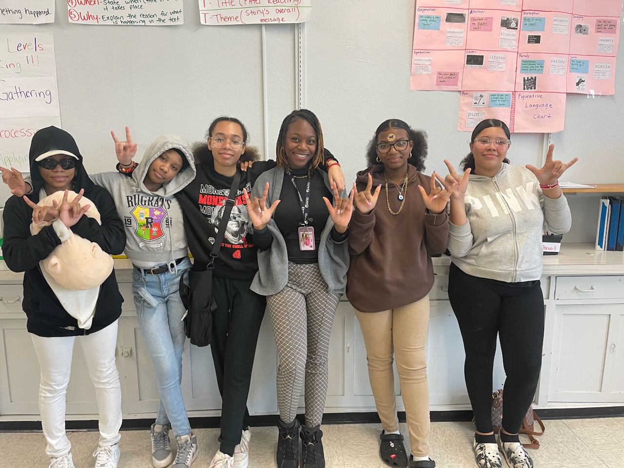 This is a photo of a group of Syracuse STEM at Blodgett students and their teacher, holding up the ASL sign for I love you.