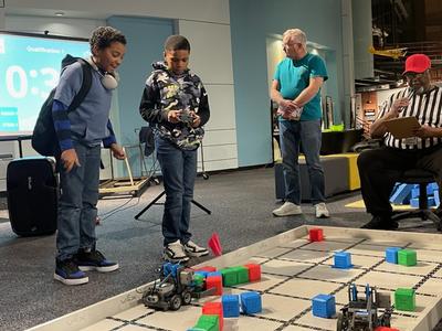 This is a photo of two students controlling their robot in a competition at the MOST.