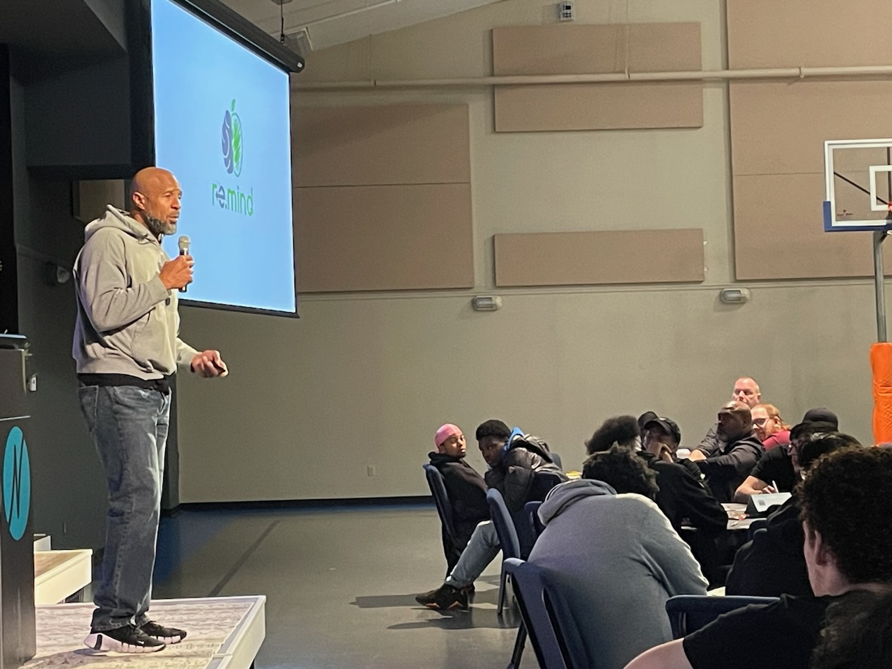 This is a photo showing NFL legend Dorsey Levens speaking to a group of SCSD high school students, who are all seated around tables watching him speak.
