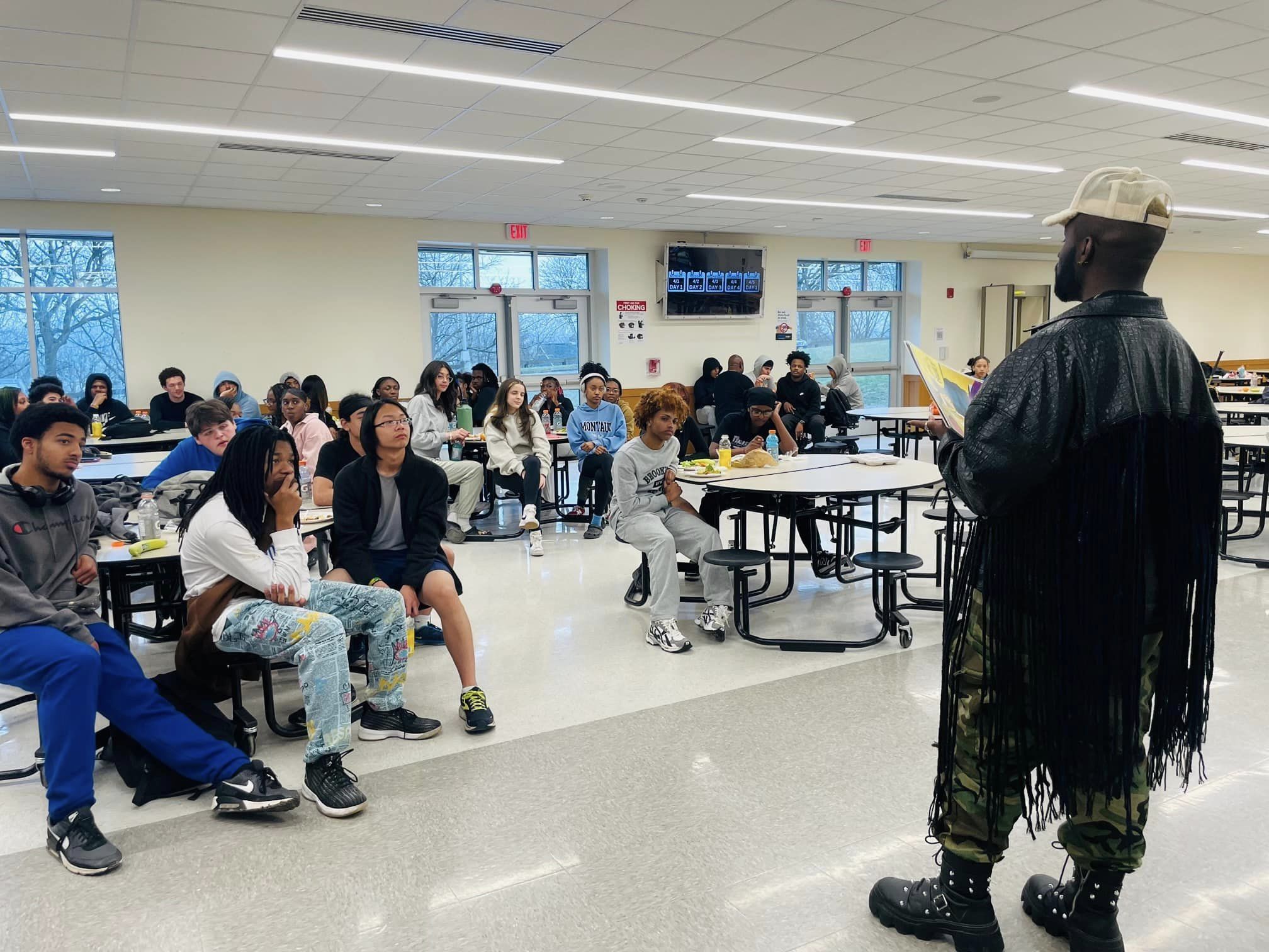 This is a photo of a guest speaker talking to a cafeteria full of Henninger student athletes.