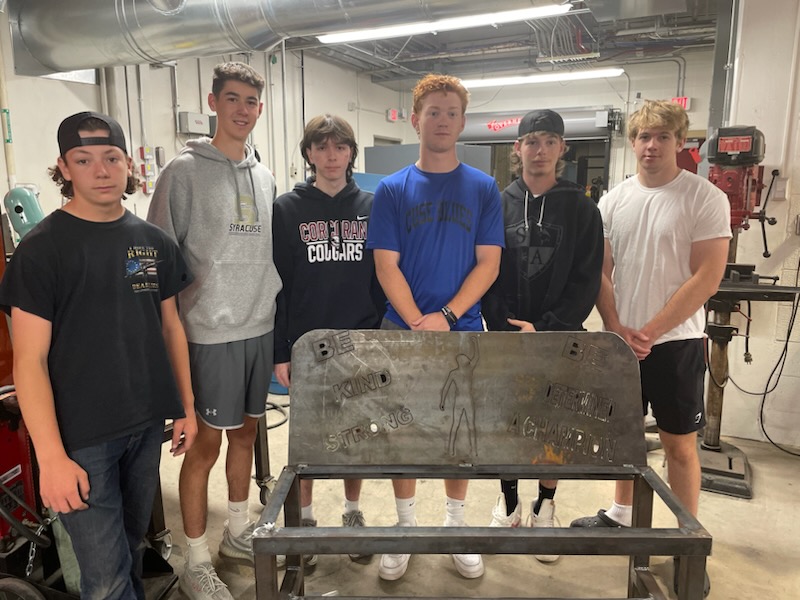 This is a photo of six Corcoran welding students standing behind a bench they welded.