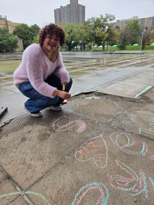 This is a photo of an ITC student drawing a message of hope on the sidewalk.