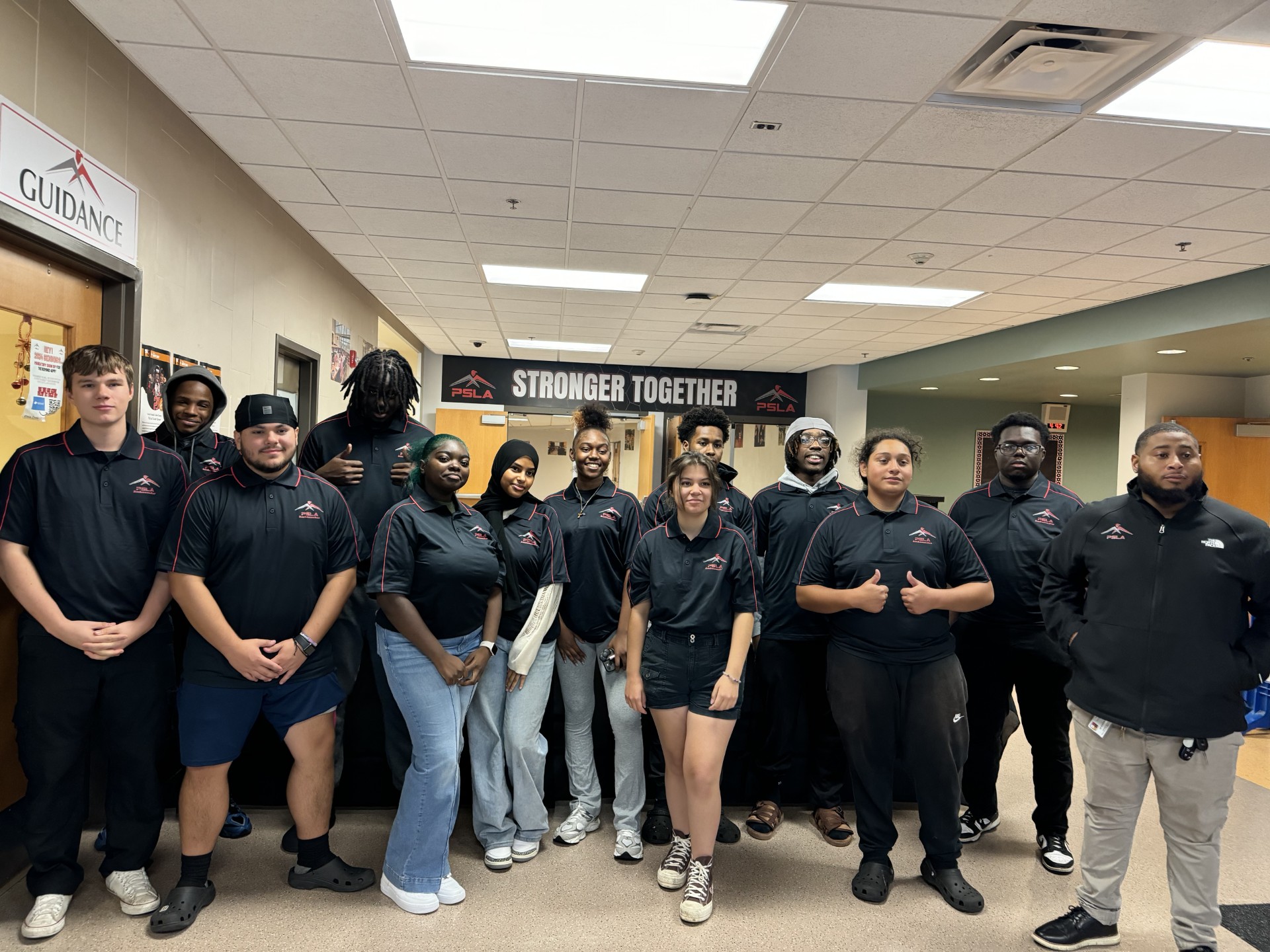 This is a photo of PSLA seniors standing in their school's foyer and smiling at the camera.