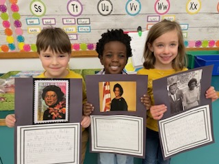 This is a photo of three Syracuse Latin students holding their Above Ground Railroad project and smiling at the camera.