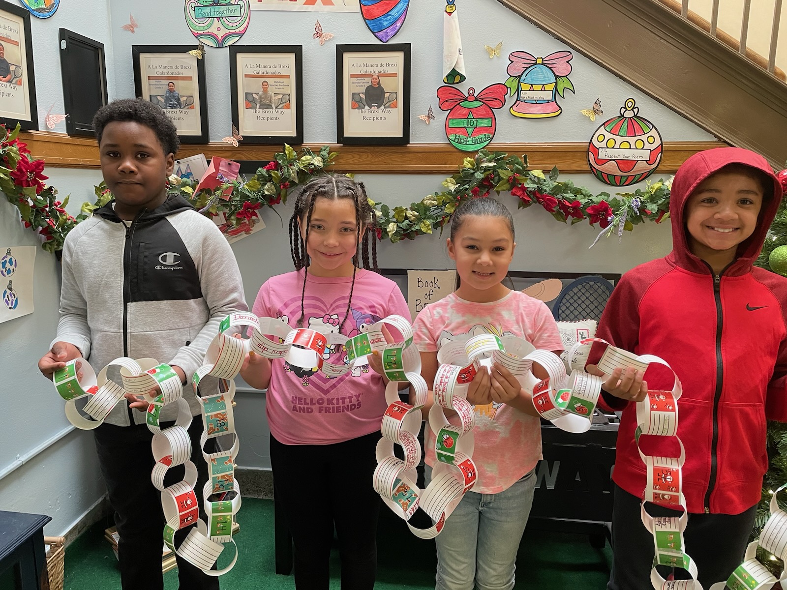 This is a photo of 4 Seymour students each holding a portion of the school's kindness chain and smiling at the camera.