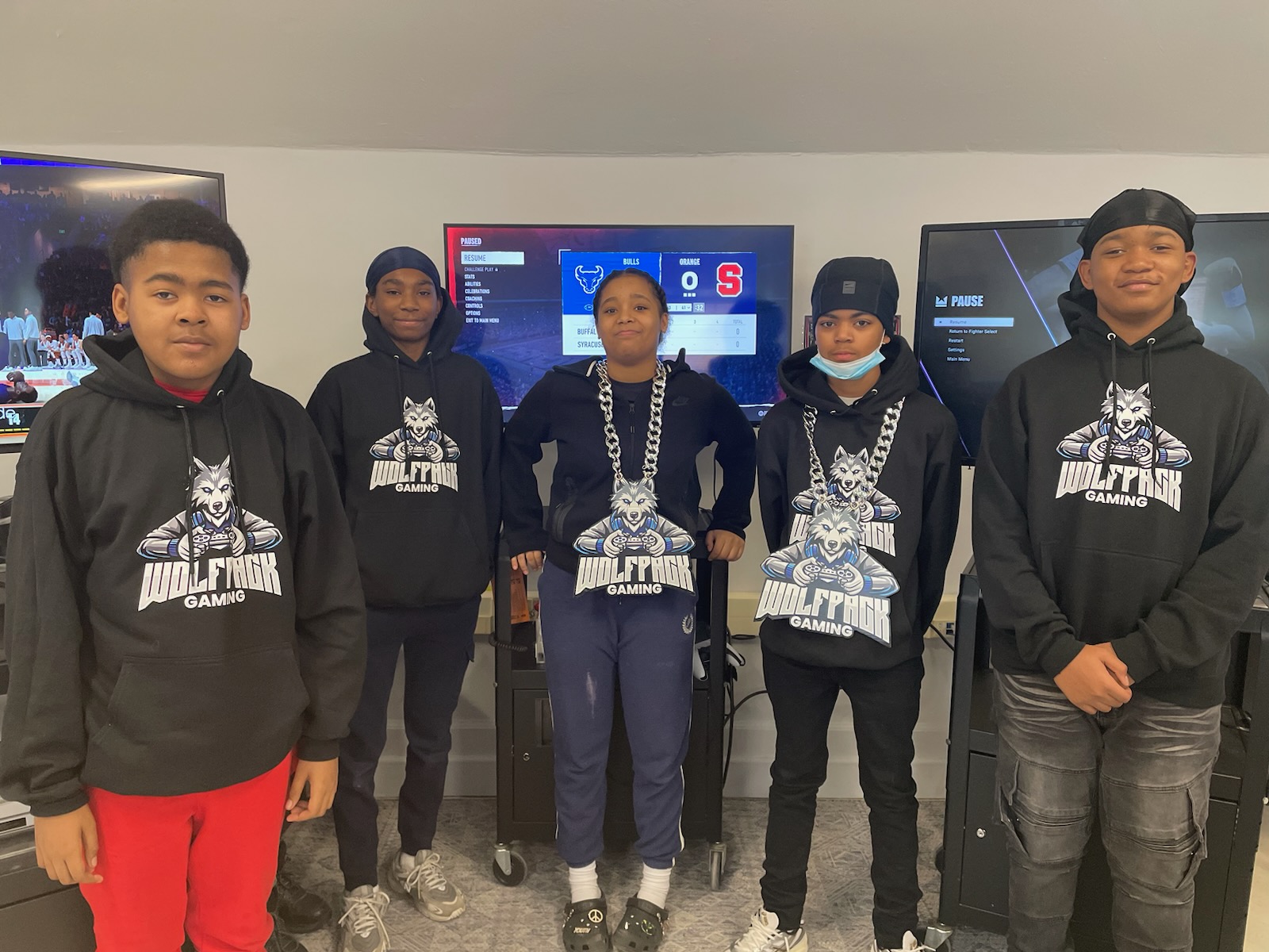 This is a photo of several Brighton Academy students standing in front of gaming consoles at a Wolfpack Gaming Club meeting.