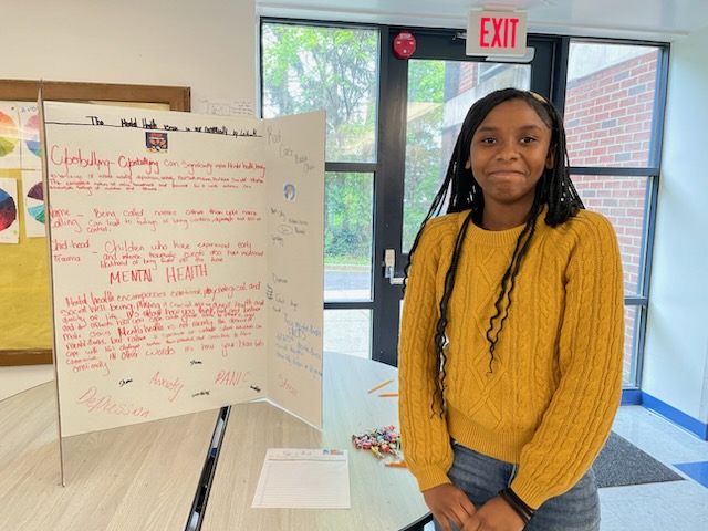 This is a photo of a Roberts student standing next to a poster she created.