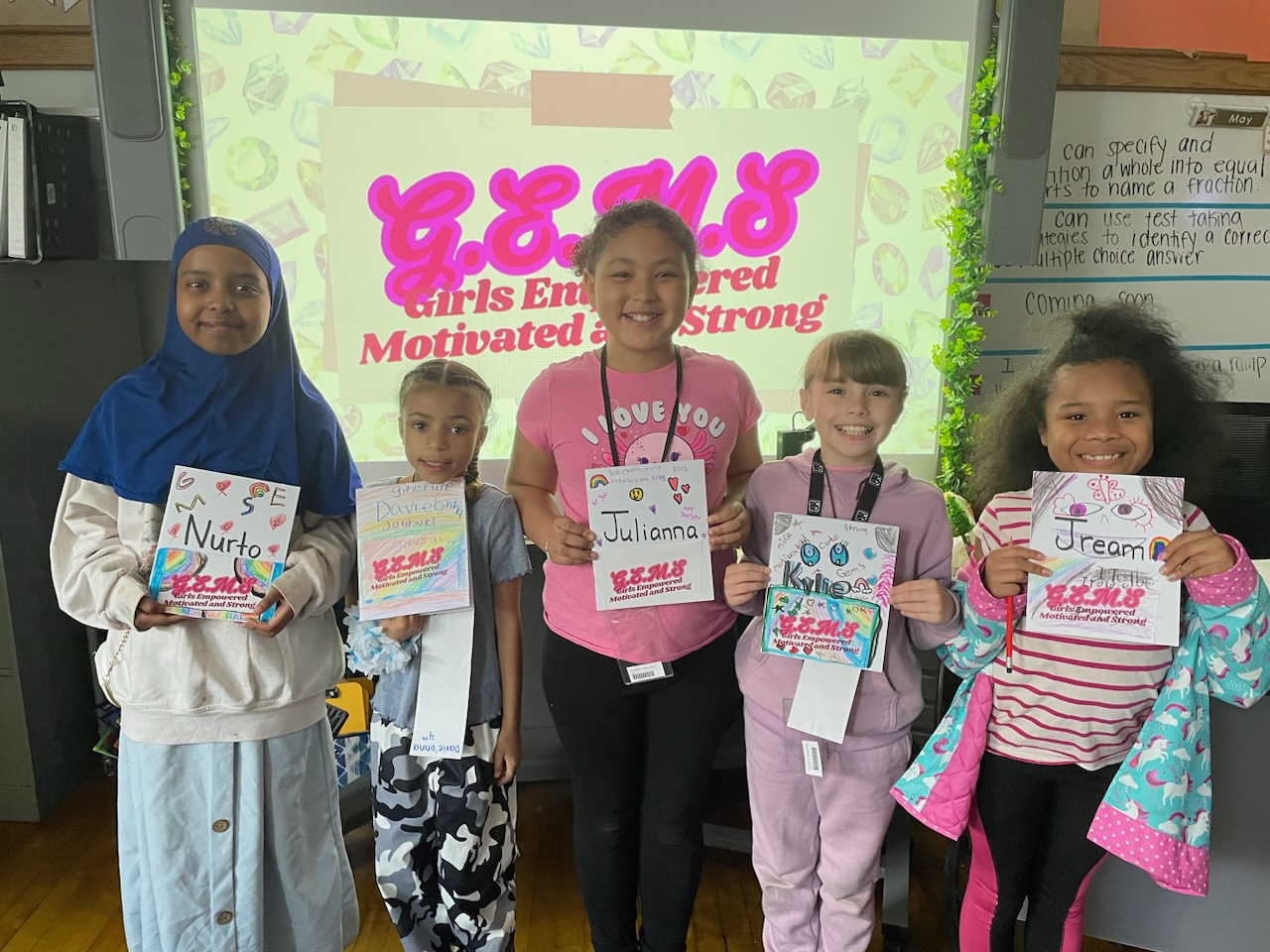 This is a photo of girls from the Porter GEMS group, each smiling at the camera while holding the cover of the journal they decorated.
