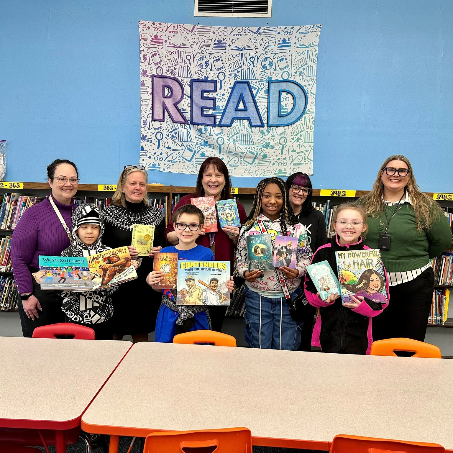 This is a photo of several SCSD students and staff, holding a collection of books written by Native American authors.