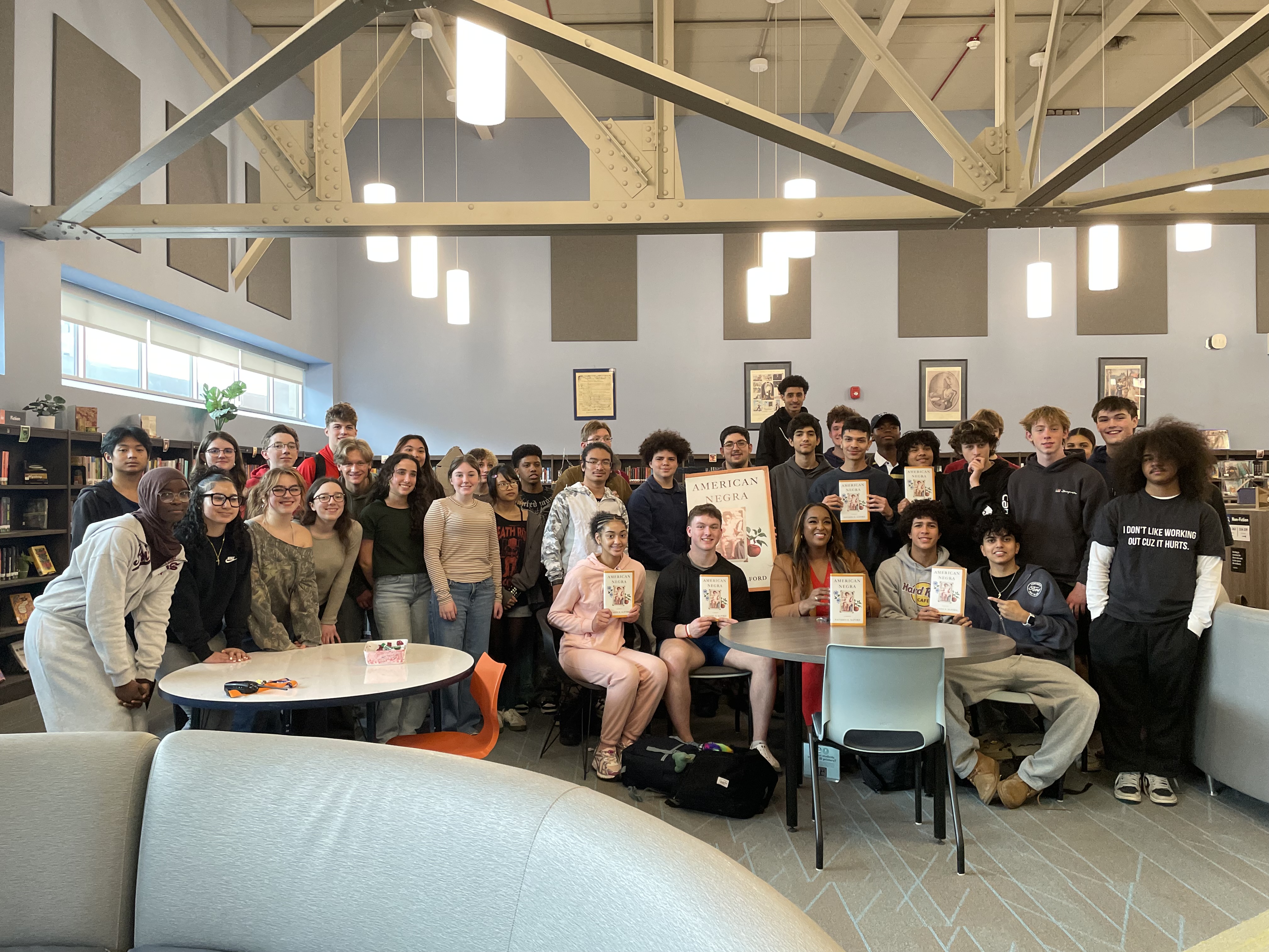 This is a photo of Nottingham alumna Natasha Alford posing with a class of Nottingham High School students in the school library.
