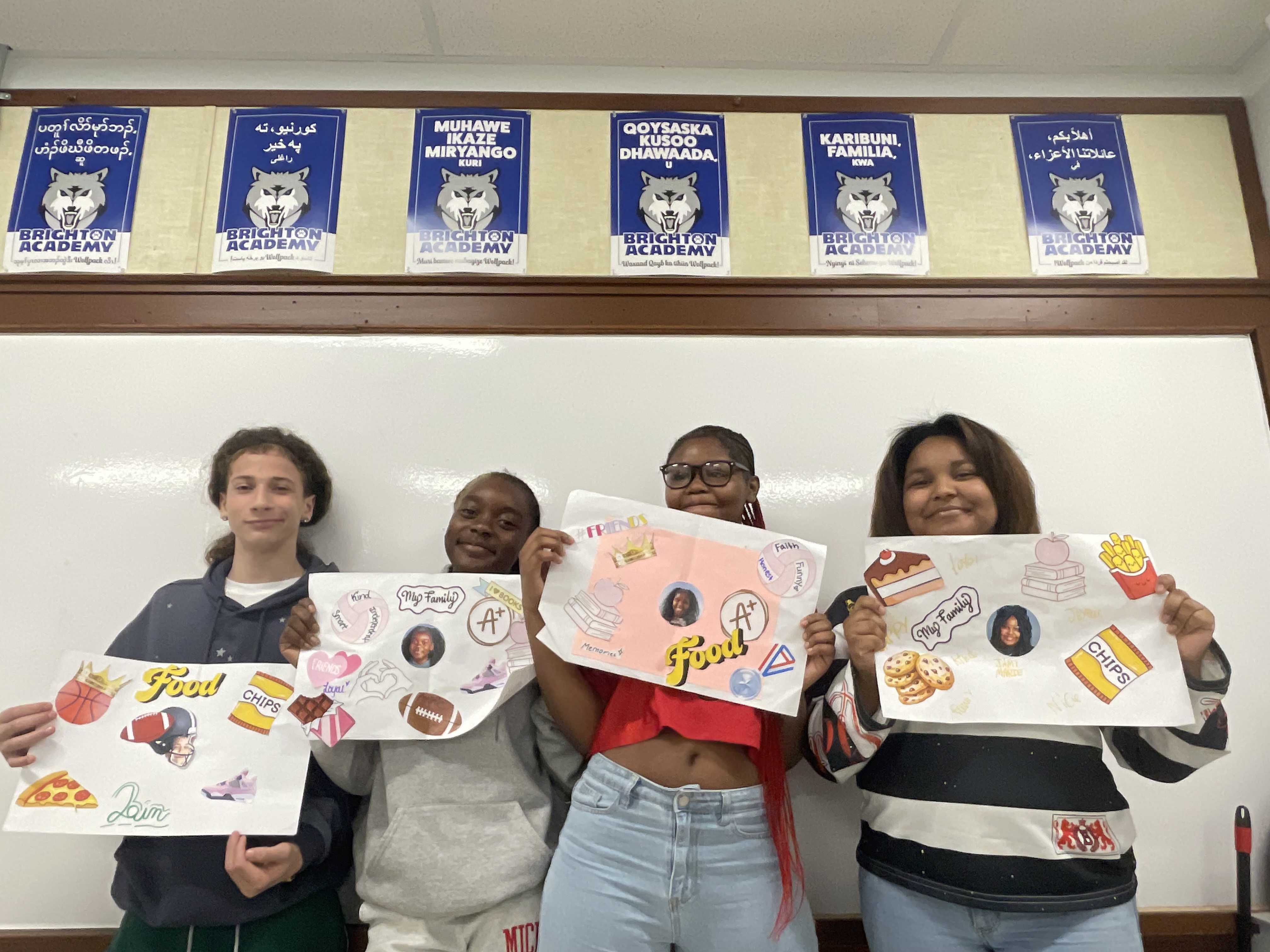This is a photo of four Brighton Academy students, each holding a poster they made highlighting their personal attributes that make them feel proud.
